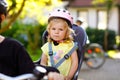 Portrait of little toddler girl with security helmet on the head sitting in bike seat of parents. Boy on bicycle on Royalty Free Stock Photo