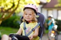 Portrait of little toddler girl with security helmet on the head sitting in bike seat of parents. Boy on bicycle on Royalty Free Stock Photo