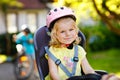 Portrait of little toddler girl with security helmet on the head sitting in bike seat of parents. Boy on bicycle on Royalty Free Stock Photo