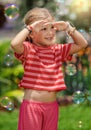 Portrait of little toddler hippie laughing girl covering her face with palms from the sun