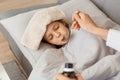 Portrait of little unhealthy girl lying on cough and drinking syrup, mother taking care of her sick daughter with towel on Royalty Free Stock Photo