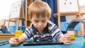 Portrait of little 4 years old boy lying on carpet in his room and using digital tablet computer