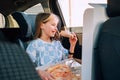 Portrait of little 5 YO girl eating just cooked Italian pizza sitting in child car seat on car back seat and looking out window . Royalty Free Stock Photo