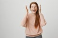 Portrait of lively charming redhead girl with cute freckles smiling broadly, looking aside and making some weird