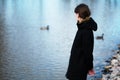 Portrait of a lonely girl by the lake. She stands in black cloth Royalty Free Stock Photo