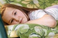 Portrait of lonely little girl with sad face lying down outside in summer. Bored child looking out with deep in thought Royalty Free Stock Photo