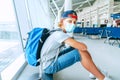 Portrait of lonely teen solo traveler with a backpack in empty airport passenger transfer hall in protective face mask and sadly Royalty Free Stock Photo