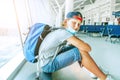 Portrait of lonely teen solo traveler with a backpack in empty airport passenger transfer hall in protective face mask and sadly Royalty Free Stock Photo