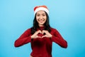 portrait, Long-haired asian girl red long-sleeved top wearing christmas hats, bring both hands her cheeks, making heart shapes on Royalty Free Stock Photo