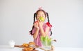 Portrait of lovely Asian little girl smell the apples with bowl of vegetables and bread on table and stand in front of white wall
