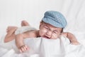 Lovely baby boy wearing cap with glasses crying on bed Royalty Free Stock Photo