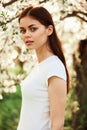 portrait of a lovely, beautiful woman against the backdrop of a flowering tree in a white T-shirt