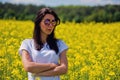 Portrait of lovely brunette in sunglasses stay in rapeseed field. Royalty Free Stock Photo