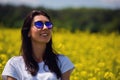 Portrait of lovely brunette in sunglasses stay in rapeseed field. Spring. Royalty Free Stock Photo