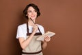 Portrait of lovely cheerful minded girl seller creating new menu writing order service isolated over brown color