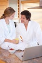 Portrait of a lovely couple having breakfast while using a notebook Royalty Free Stock Photo