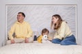 Portrait of lovely family, friendly parents, mom and dad with adorable child son and white dog sitting on the bed together Royalty Free Stock Photo