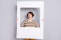 Portrait of lovely funny girl holding in hands big photo frame fooling having fun isolated over grey pastel color