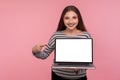 Portrait of lovely happy woman in striped sweatshirt holding laptop with blank display, showing empty screen Royalty Free Stock Photo