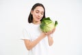 Portrait of lovely korean woman, showing cabbage, holding lettuce green vegetable and smiling, isolated on white Royalty Free Stock Photo