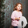 Portrait of a lovely little girl. cute little girl among Christmas decorations. Girl riding a rocking deer. Rocking deer chair Royalty Free Stock Photo