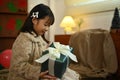 Portrait of lovely little girl opening Christmas gift boxes while sitting on the floor near the Christmas tree Royalty Free Stock Photo