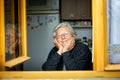 Portrait of lovely senior woman or grandmother watching out from the window and smiling, pensioner Royalty Free Stock Photo