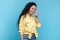 Portrait of lovely smiling young woman making Korean finger mini heart gesture on blue background