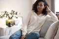 Portrait of lovely young mixed race woman smiling and looking at camera, sitting on sofa at home Royalty Free Stock Photo