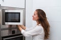 Portrait of a lovely young modern woman cooking in the microwave oven. Royalty Free Stock Photo