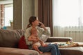 Woman talking on mobile phone holding baby on her knees Royalty Free Stock Photo