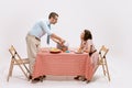 Portrait of loving couple sitting at the table, having breakfast on white background. Look of love