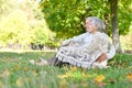 Portrait of loving elderly couple sitting on green grass in the summer park