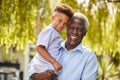 Portrait Of Loving Grandfather Holding Grandson In Arms In Garden At Home