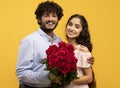 Portrait of loving indian couple with bunch of flowers smiling and looking at camera, celebrating Valentine& x27;s Day