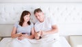 Portrait of loving middle aged couple smiling and watching something on a mobile phone in bedroom Royalty Free Stock Photo