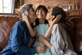 Portrait of loving mom and grandmother kiss small child