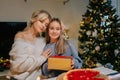 Portrait of loving mother hugging adorable little daughter after giving Christmas present to adorable daughter sitting Royalty Free Stock Photo