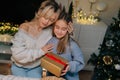 Portrait of loving mother hugging smiling little daughter after giving Christmas present to adorable daughter during Royalty Free Stock Photo