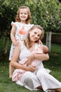 Portrait of loving mother and two adorable kids. little girl and newborn baby girl with mom outdoors on summer day. Happy family Royalty Free Stock Photo