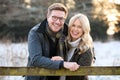 Portrait Of Loving Newly Engaged Couple Leaning On Fence On Snowy Walk In Winter Countryside