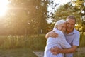 Portrait Of Loving Senior Couple Hugging Outdoors In Summer Park Against Flaring Sun Royalty Free Stock Photo