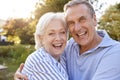 Portrait Of Loving Senior Couple Hugging Outdoors In Summer Park Against Flaring Sun Royalty Free Stock Photo