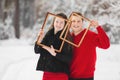 Portrait of loving young couple having fun in winter snowy forest and holding photo frames. concept of family and love Royalty Free Stock Photo