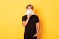 Portrait of lucky happy asian guy looking surprised and showing money, standing yellow background