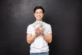 Portrait of lucky satisfied young rich asian male student holding lots of cash, fan of dollars smiling happy and pleased