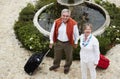 Portrait, luggage and senior couple at hotel, water fountain or holiday vacation from above. Smile, elderly man and