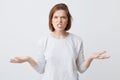 Portrait of mad irritated young woman in longsleeve feels angry and holding copyspace on both palms isolated over white background