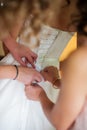 Portrait maid of honor helping the bride with her dress