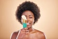 Portrait, makeup and a black woman with brushes on a studio background for wellness and foundation. Tongue out, beauty